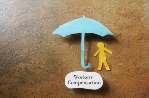 What does workers’ comp cover? Paper man under workers’ compensation umbrella