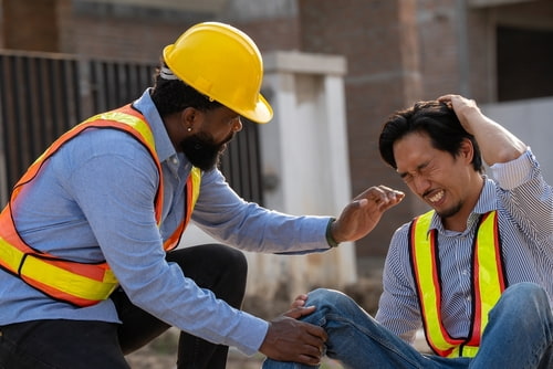 A man helps a coworker hurt in a construction accident.