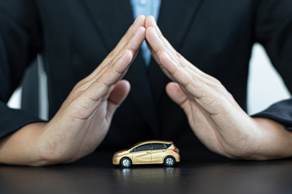 A photo of a Miami car accident lawyer protecting a toy car with their hands.