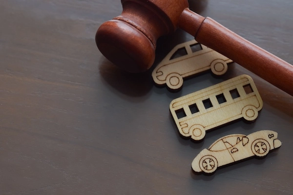 A gavel and three wooden vehicles represent a Fort Lauderdale bus accident lawyer.