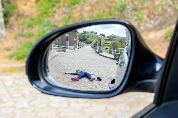 A person is lying on the ground after being hit by a car and needs a Miami pedestrian accident lawyer.