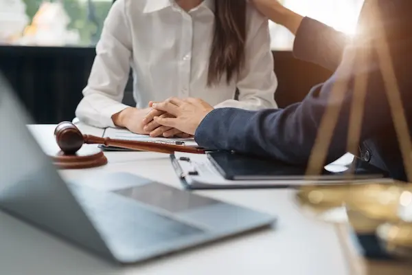 A rideshare accident lawyer is consoling a client at a desk.